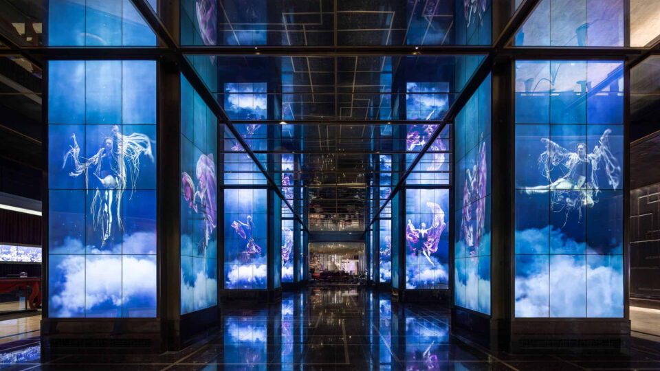 Digital displays on lobby columns showing underwater performers in vibrant costumes, from Opulence at The Cosmopolitan of Las Vegas, by Float4.