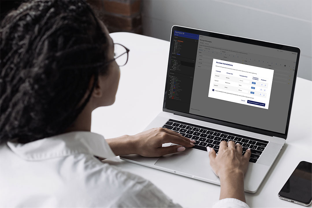 Person reviewing multilingual signage translations in SignAgent’s AI translation tool on a laptop.